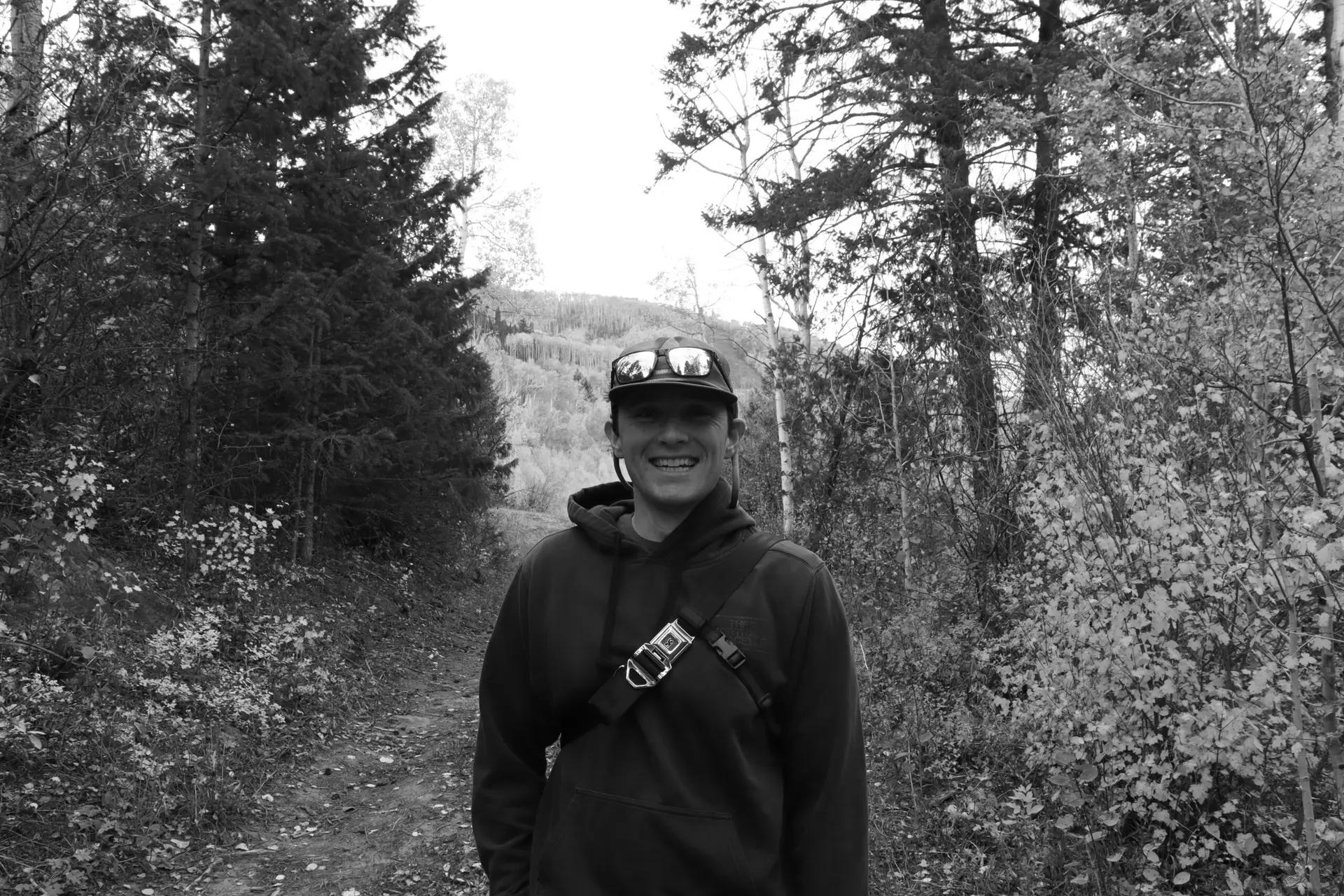 Black‑and‑white photo of a person smiling on a forest trail